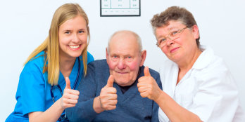 caregiver and elders showing their thumbs up
